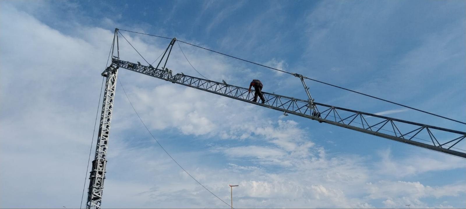 Monteur progressant sur la flèche d'une grue, harnais et longe de sécurité