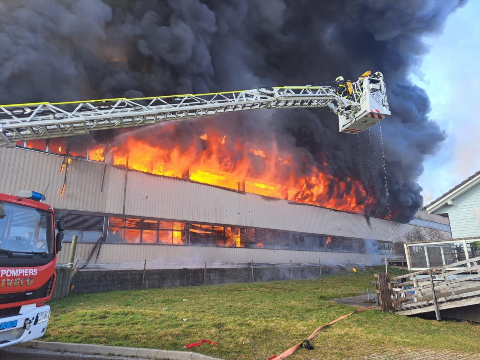 Intervention des pompiers avec échelle aérienne sur un bâtiment industriel en feu